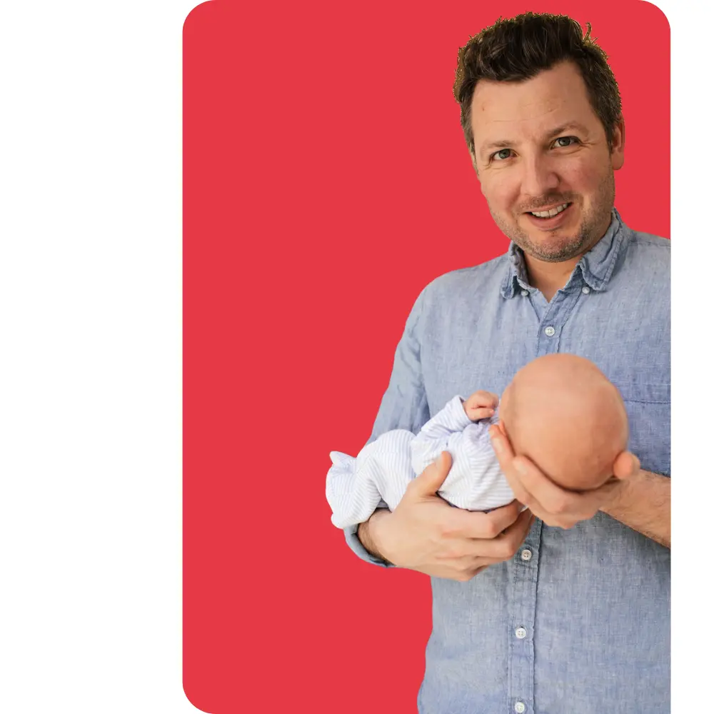 Photo of me holding my 2-month-old son against a red background.